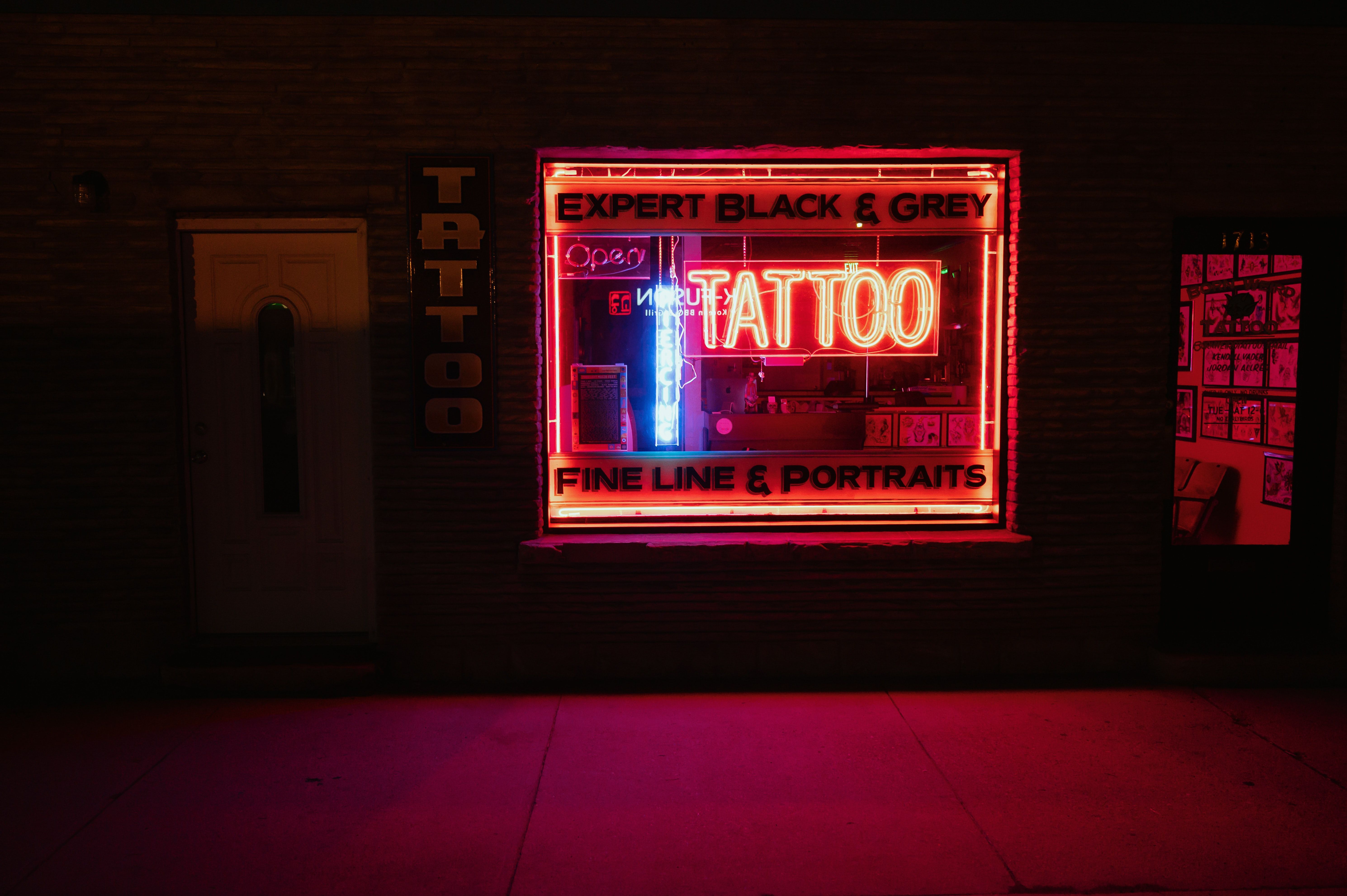 A tattoo shop with neon lights on the outside - 