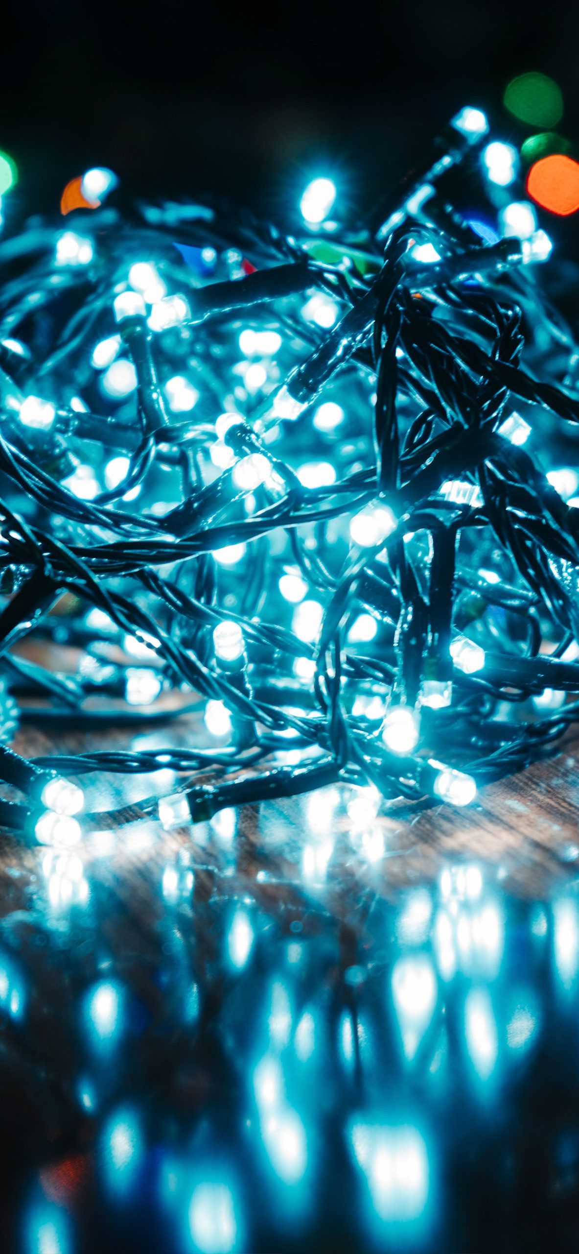 A string of blue Christmas lights on a wooden floor. - Christmas lights, fairy lights