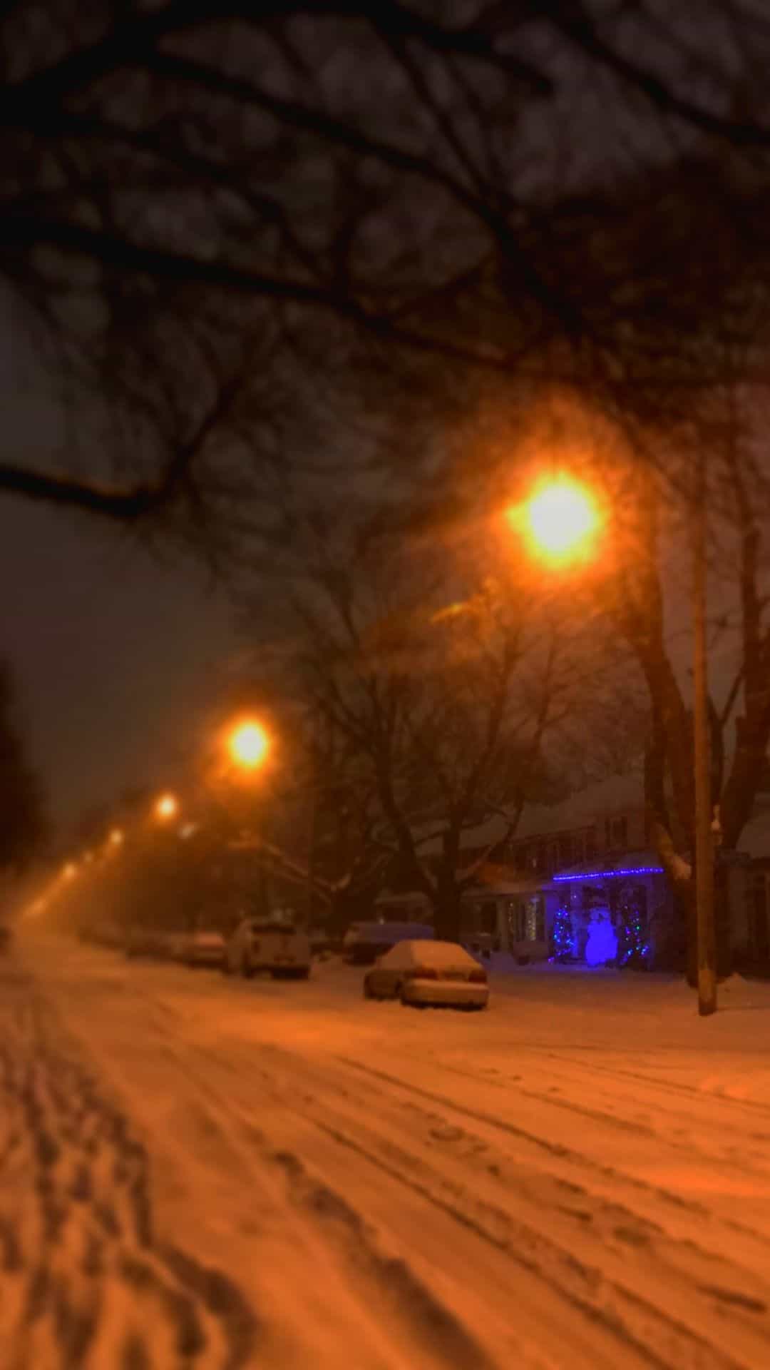 A street is covered in snow and has lights on - Christmas lights