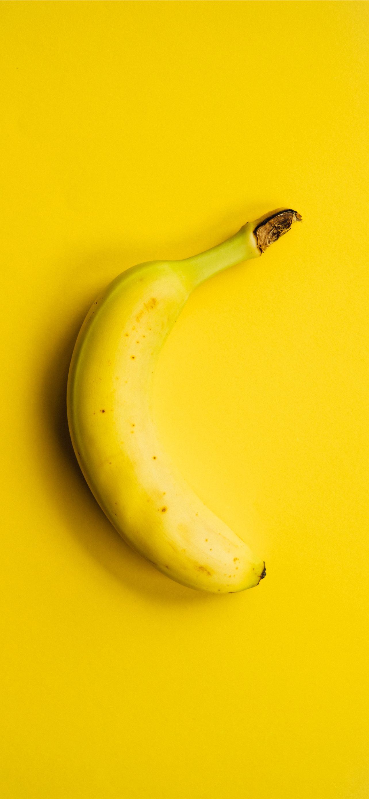 A banana is on top of yellow background - Yellow