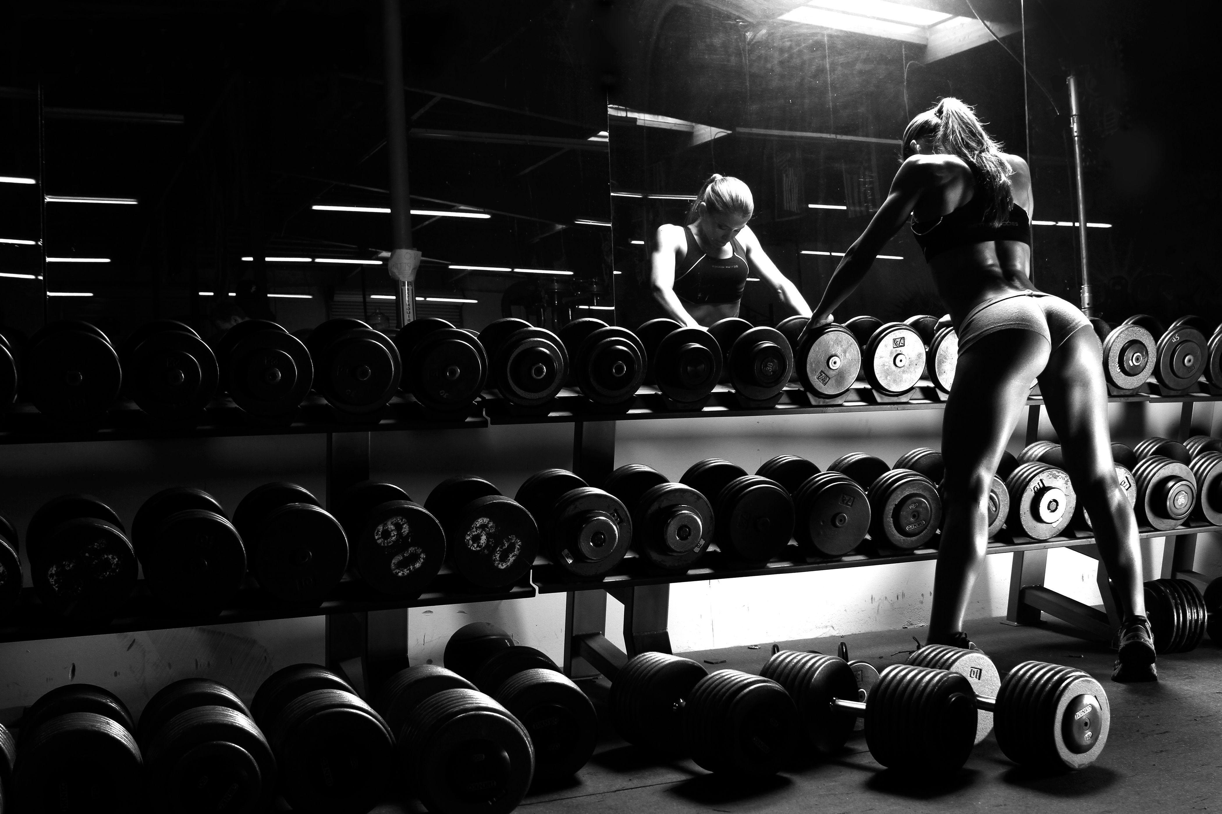 A woman is standing in front of some weights - Gym