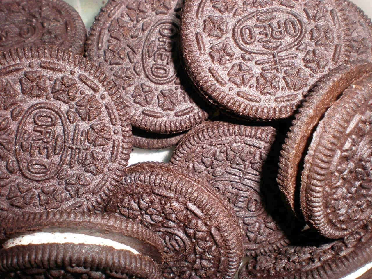 A plate of chocolate sandwich cookies with the filling visible. - Oreo