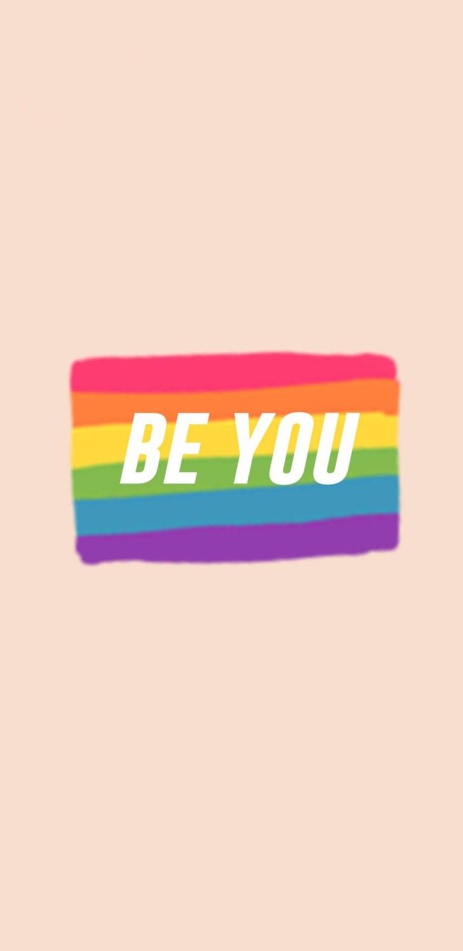 A rainbow colored be you sticker on an orange background - LGBT
