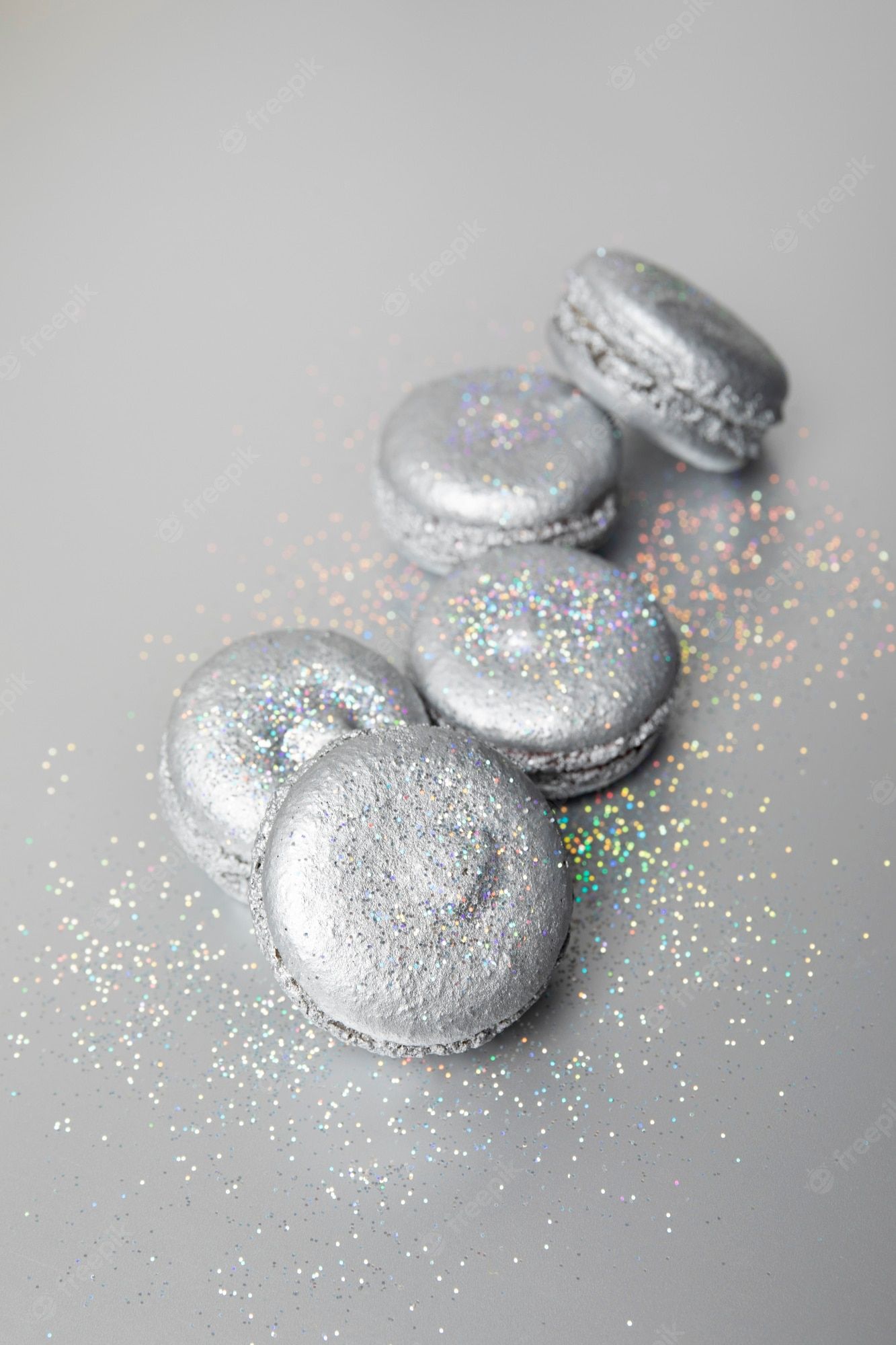 A row of silver macarons with some glitter on a grey background - Silver