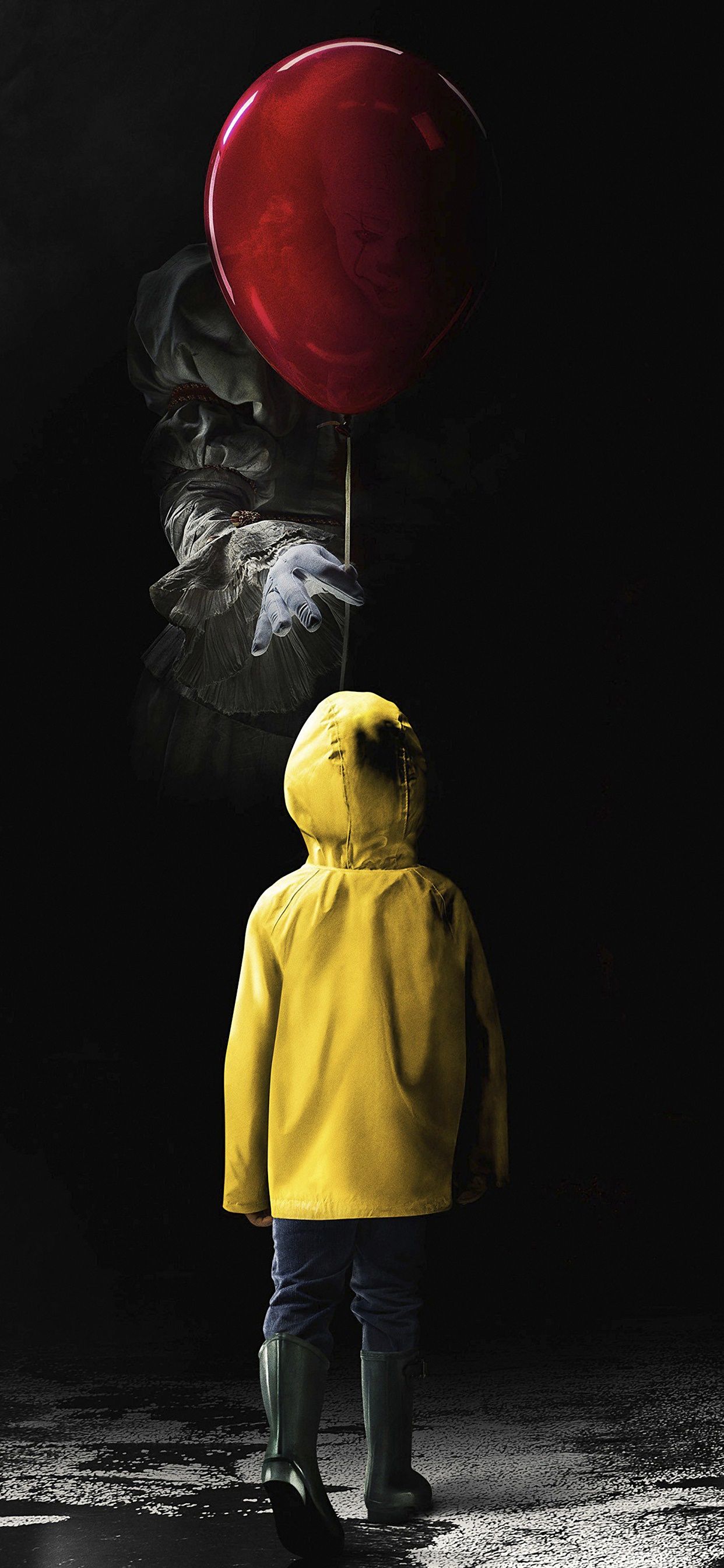 A person in yellow rain gear holding onto an inflated red balloon - Horror, clown