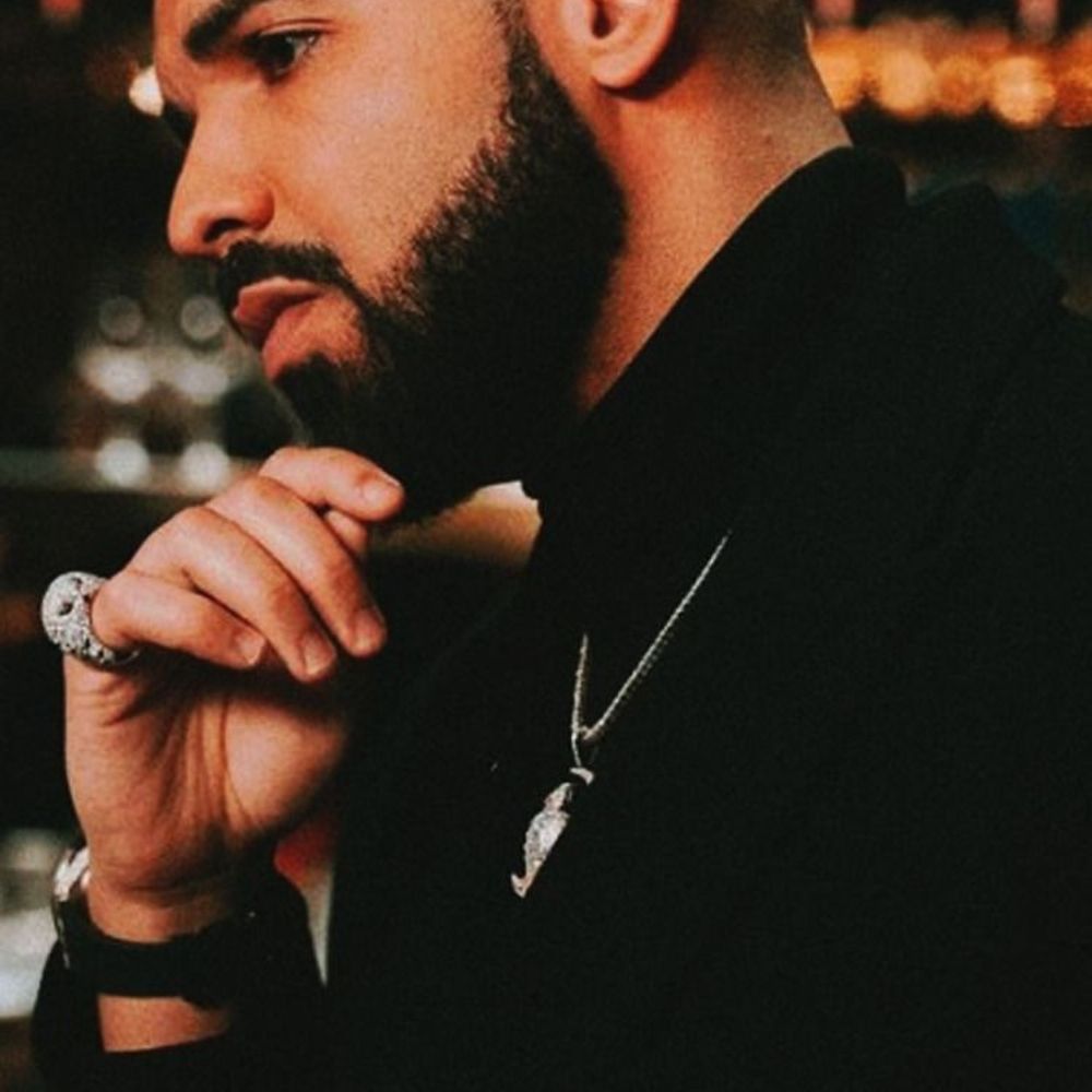 Drake wearing a black shirt and a silver chain with a pendant of a bird - Drake