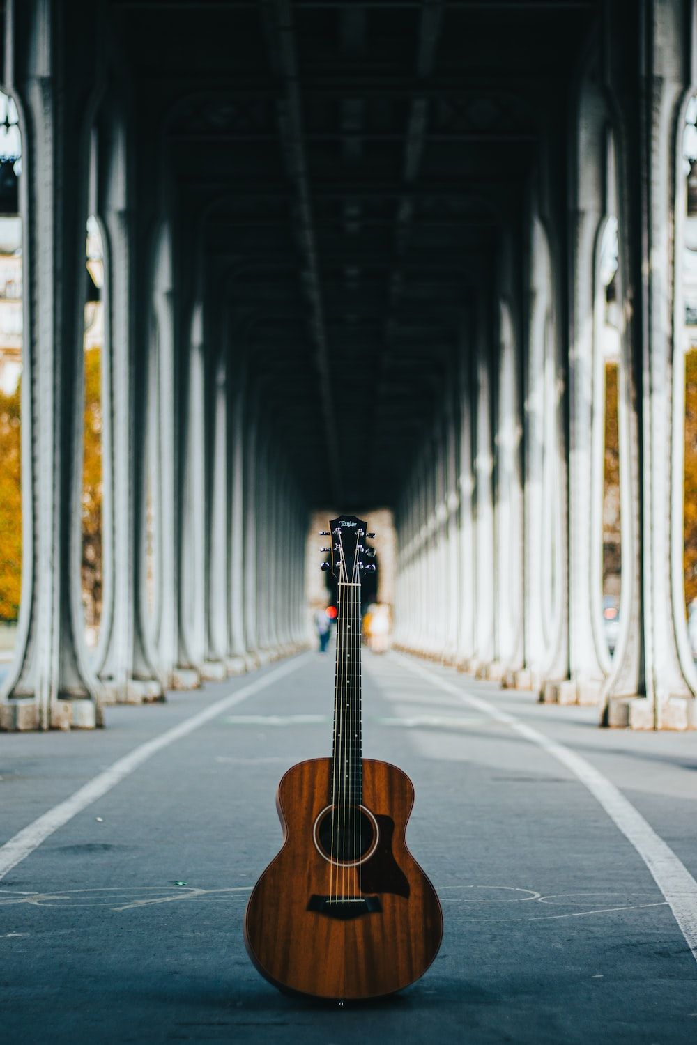 A guitar sits in the middle of a road. - Guitar