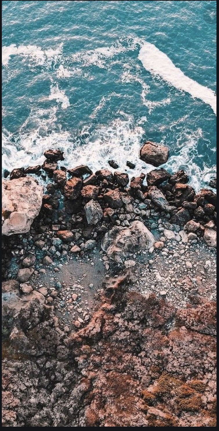 A rocky shore with waves crashing against it - Royalcore