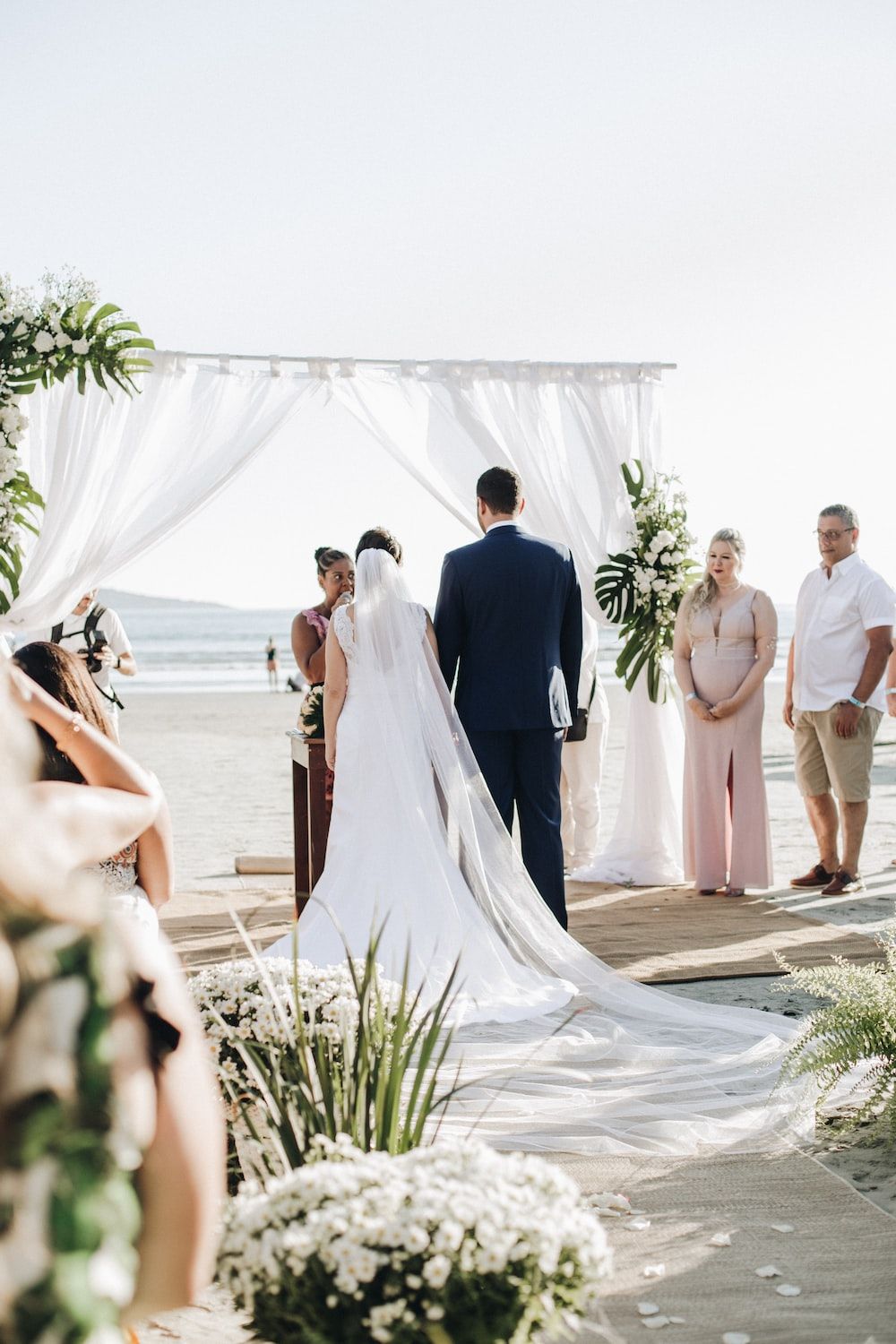 A couple getting married on the beach with a beautiful backdrop. - Wedding