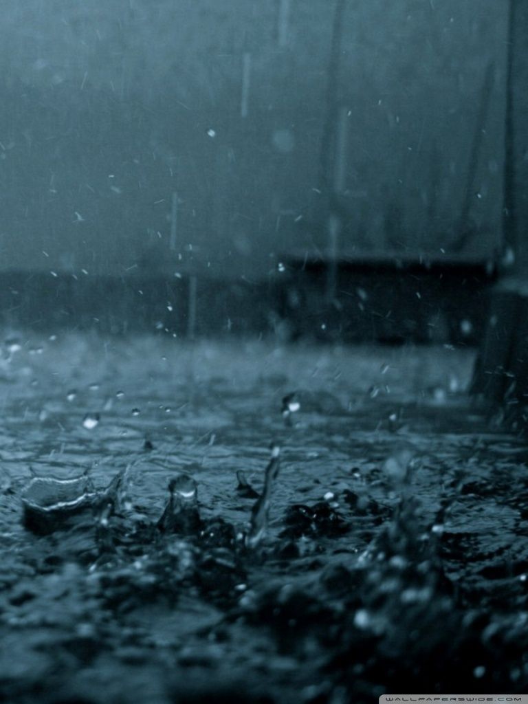 A dark and moody image of rain falling on a city street - Rain