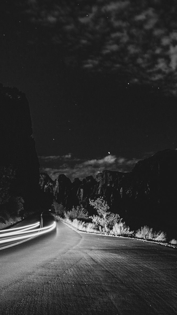 A car drives down a road in the desert at night. - Road