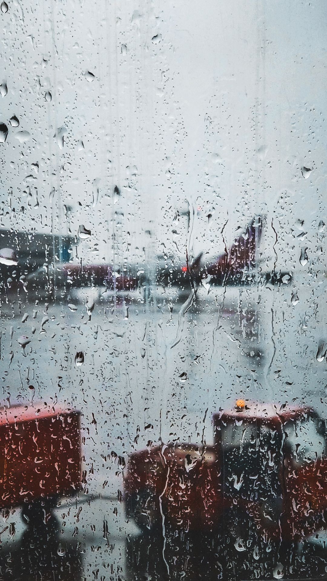 A rain covered window view of an airport - Rain