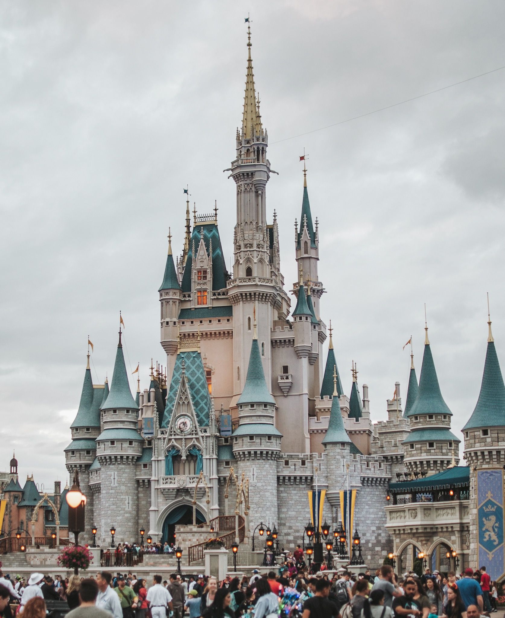 The iconic Cinderella Castle at Disney World, with a crowd of people walking around it. - Disneyland