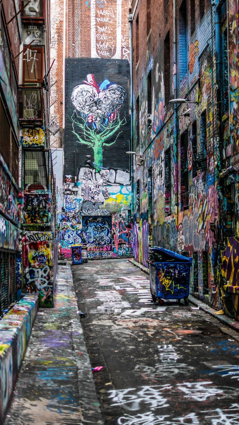 An alleyway with walls covered in graffiti - Graffiti, street art