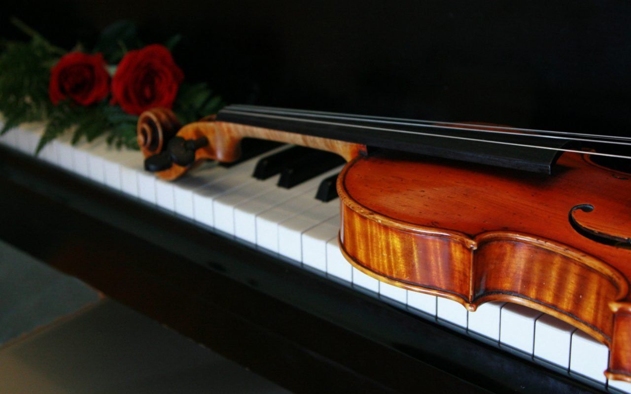 A violin is sitting on top of the piano - Piano