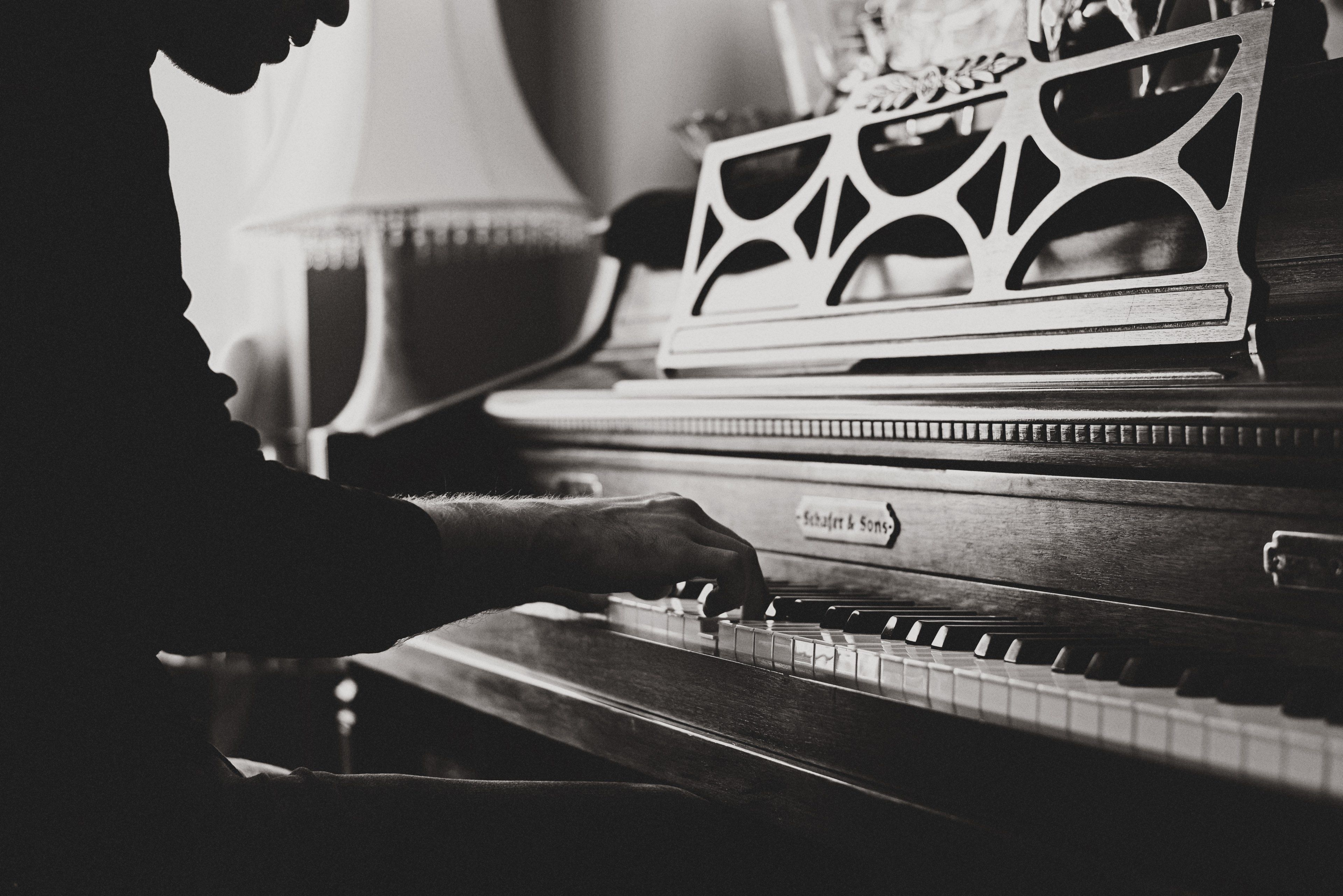 Wallpaper / a black and white shot of a man playing a vintage piano, vintage piano player 4k wallpaper free download