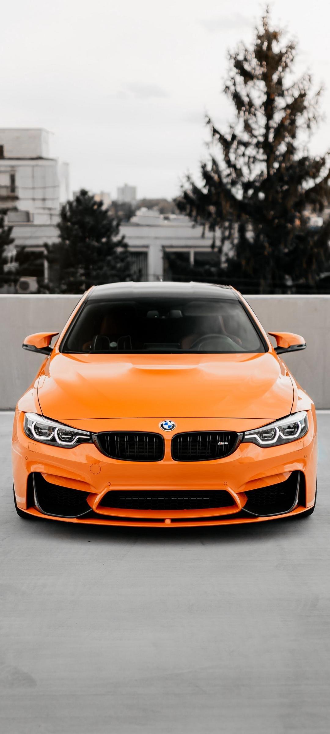 An orange bmw car is parked on a street - BMW