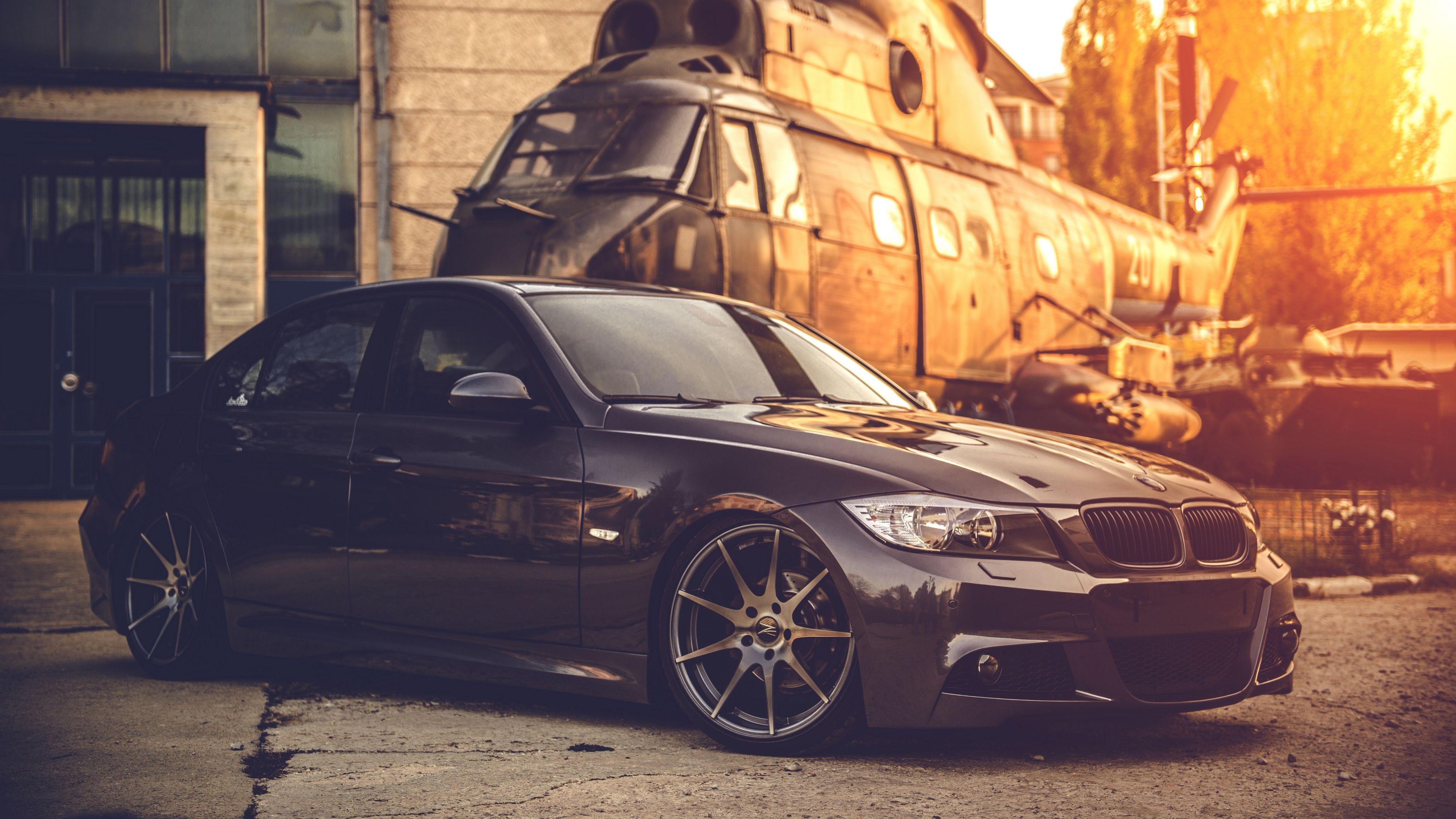 A black car parked in front of an army helicopter - BMW