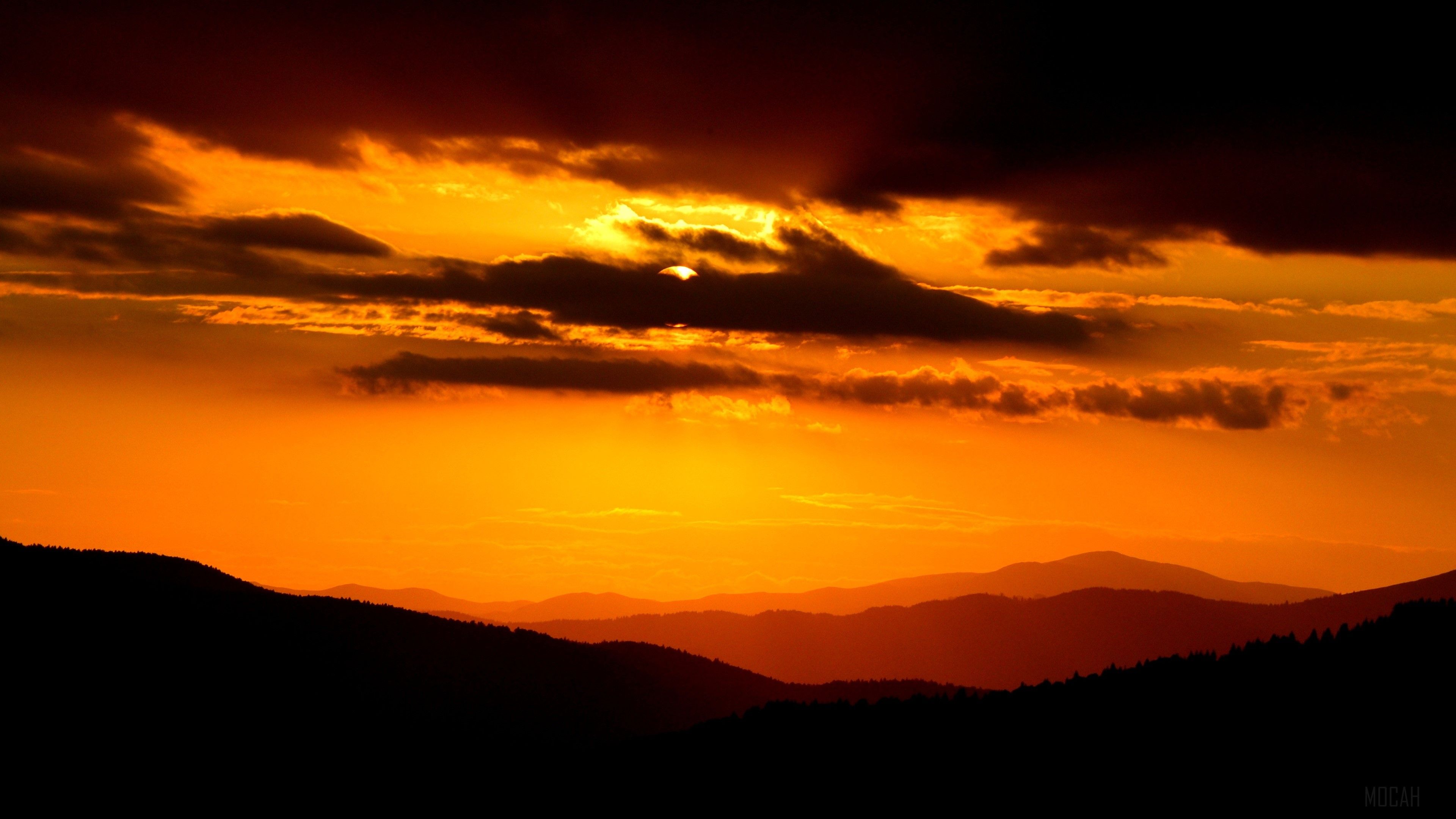 A dark orange sunset over a mountain range. - Dark orange
