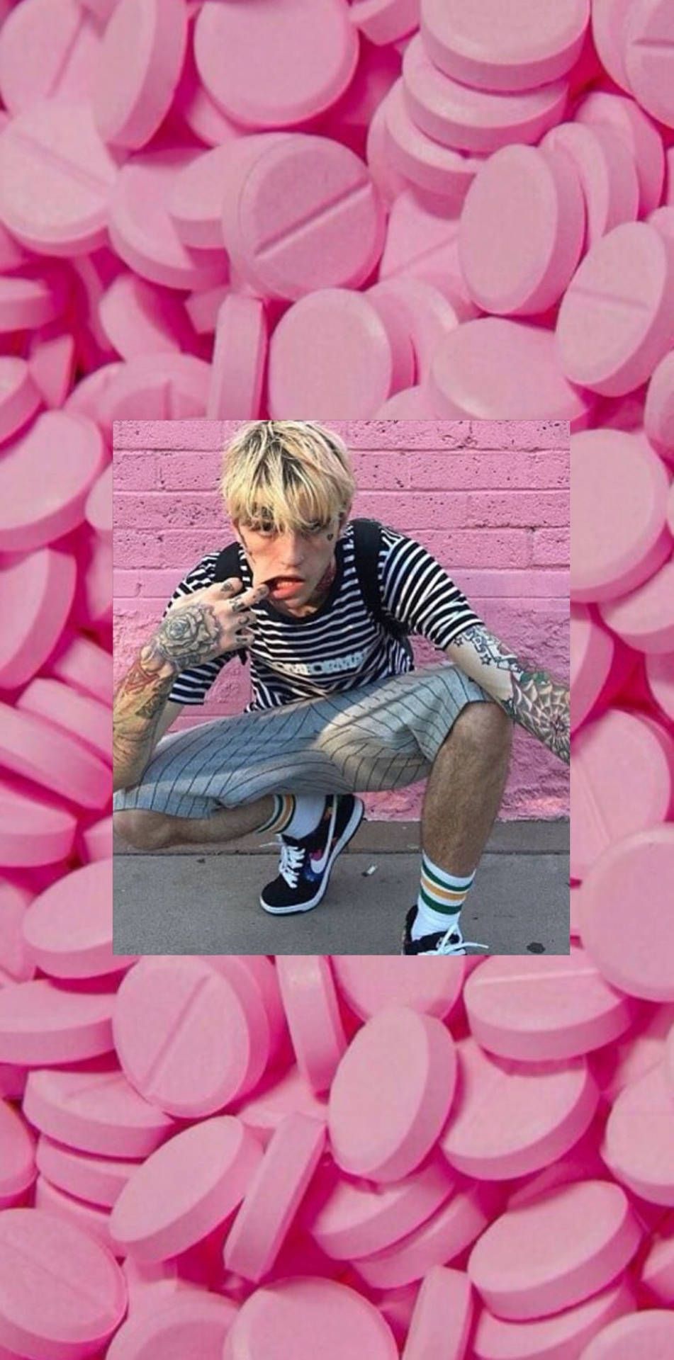 A man is sitting on the ground with pink pillows - Lil Peep
