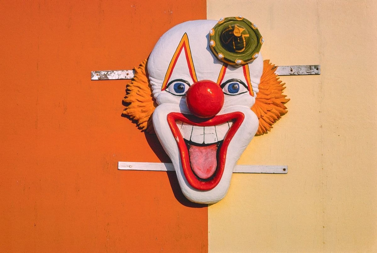 A clown mask on a wall. - Clown