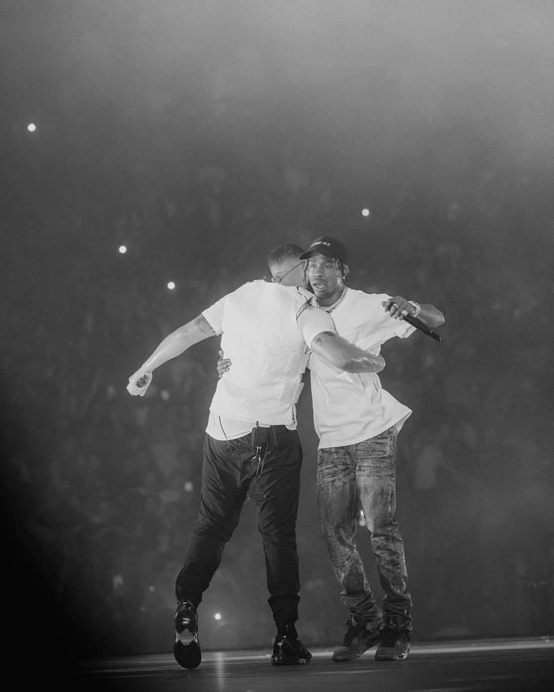 Two men hugging on a stage in front of an audience - Drake, Travis Scott