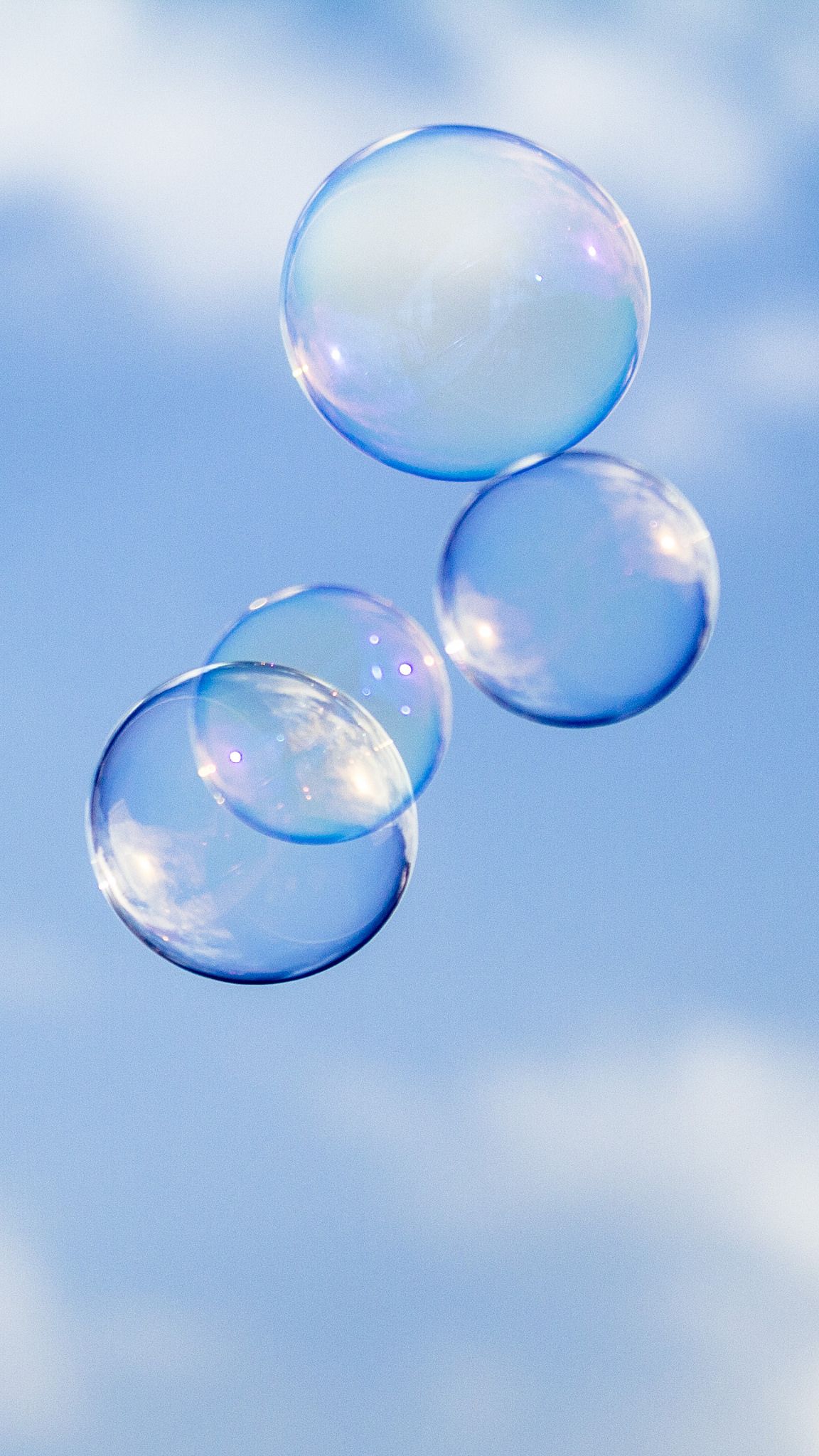 Three bubbles floating in the air against a blue sky - Bubbles