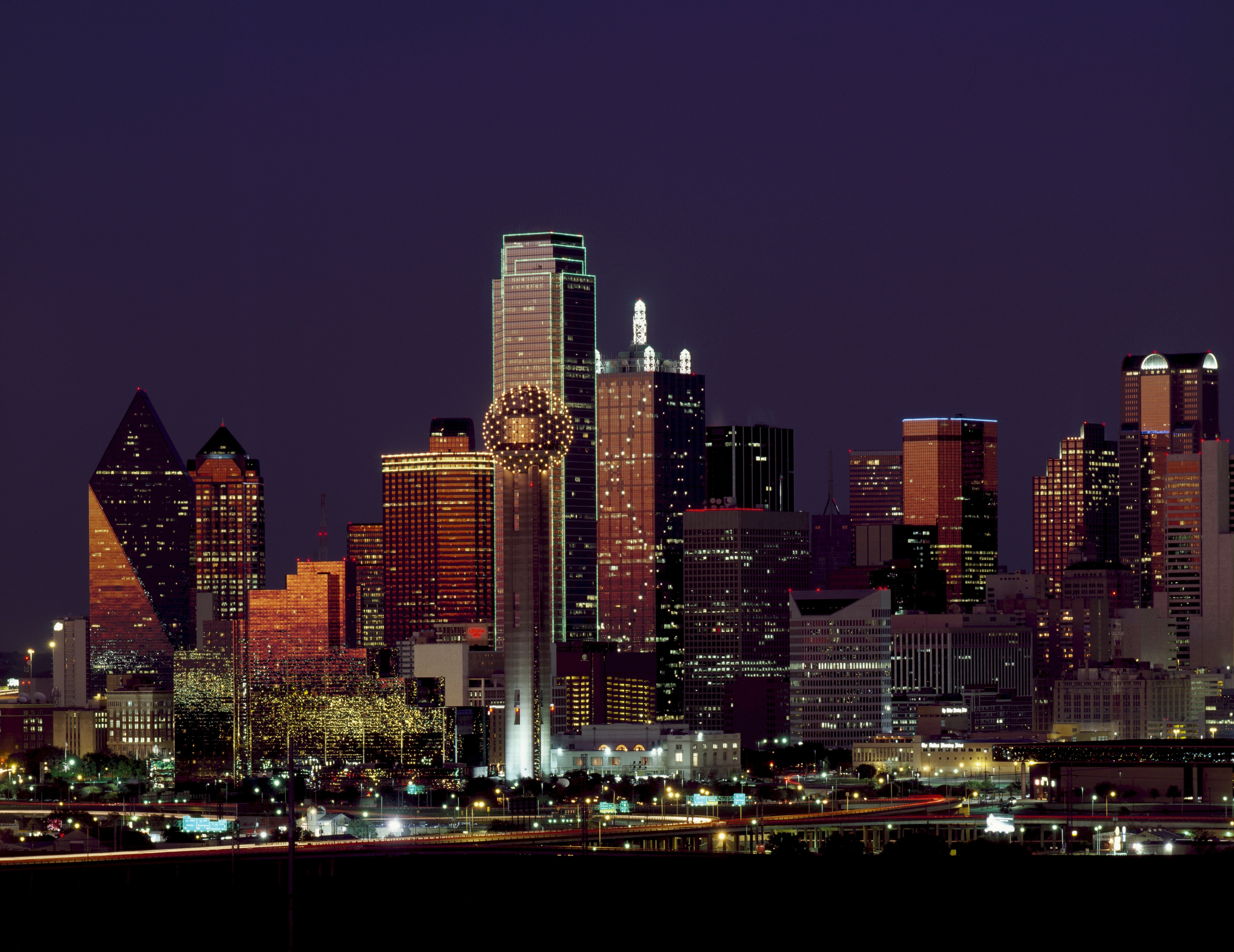 A city skyline at night with traffic on the road - Texas