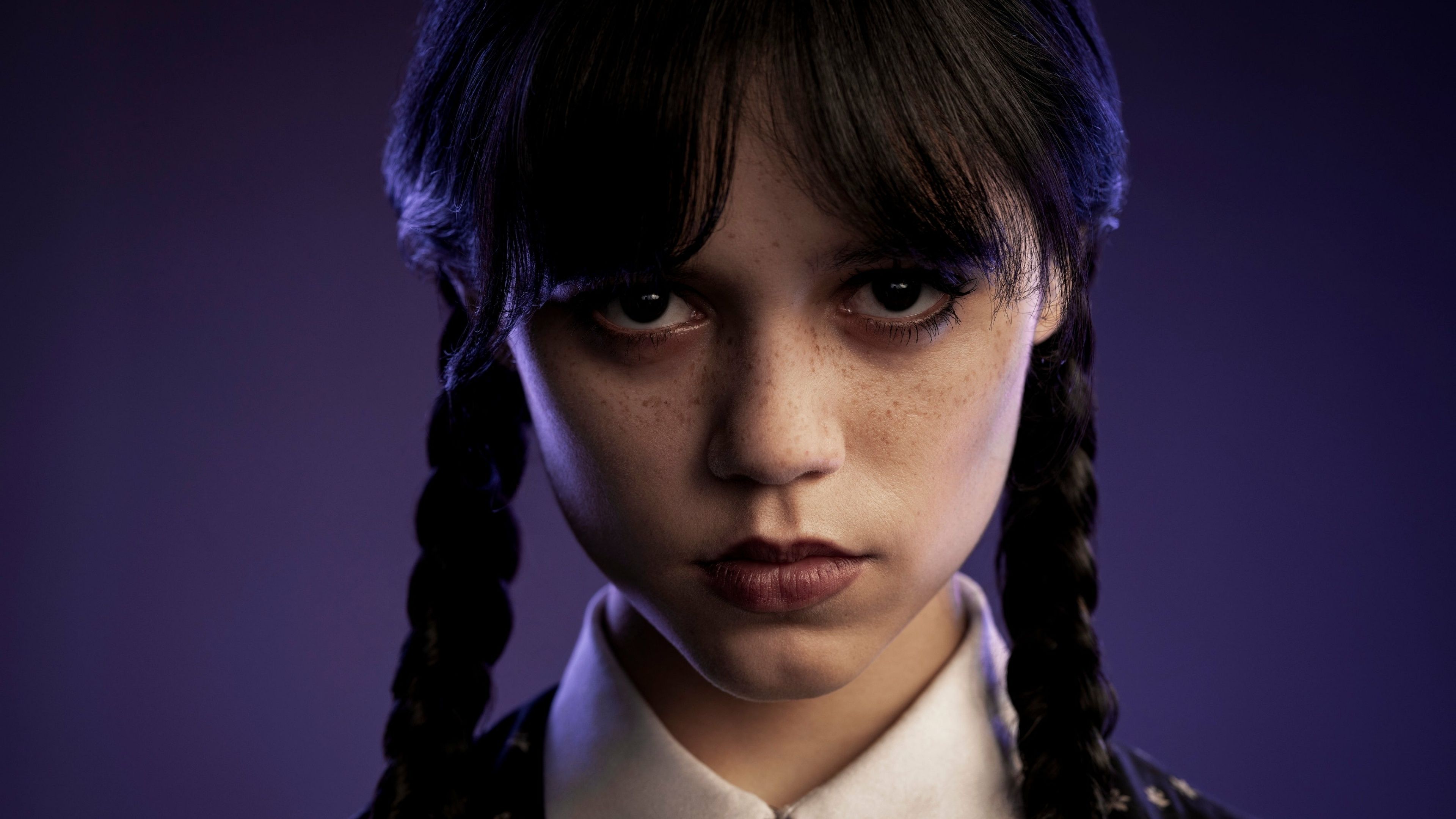 Wednesday Addams from the Addams Family staring into the camera with a purple background - Netflix, Wednesday