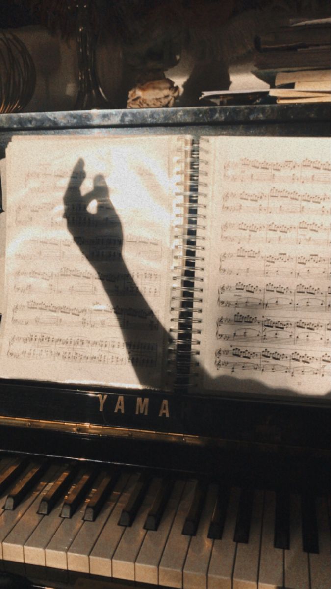 A shadow of a conductor on a music sheet on a piano. - Piano