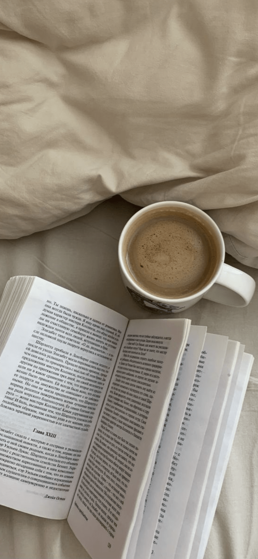 A cup of coffee sits on top of an open book on a bed. - Virgo