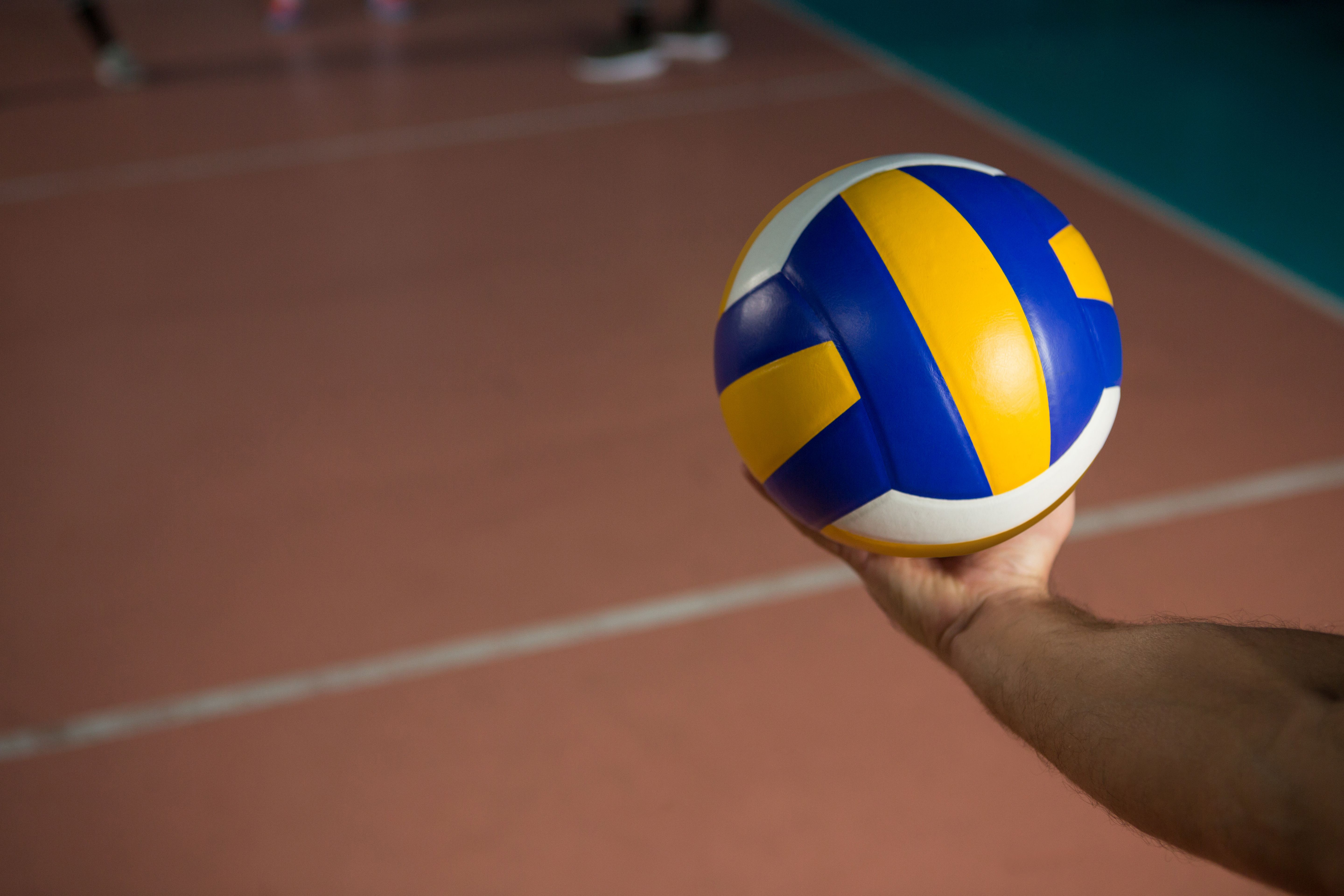 A hand holding up an volleyball ball - Volleyball