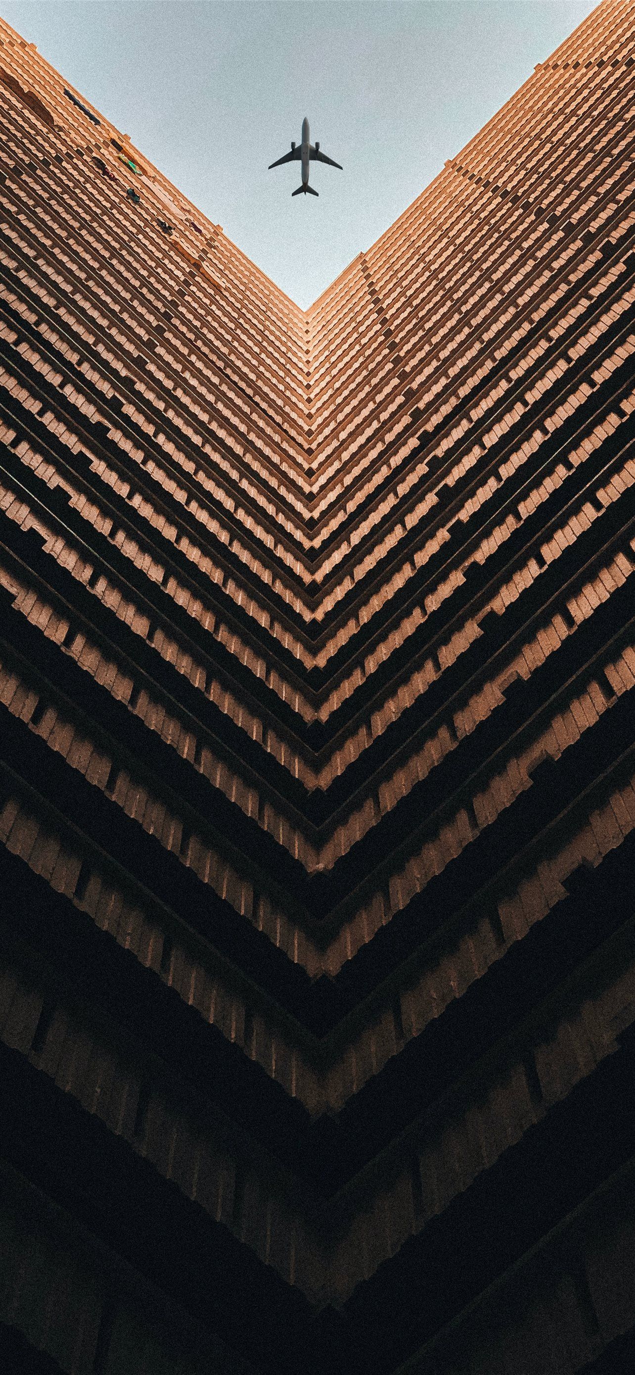 A plane flying over a large building - Travel