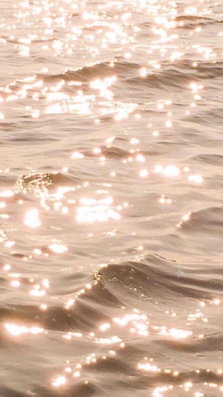 A body of water with small waves and a golden hue. - Water, gold