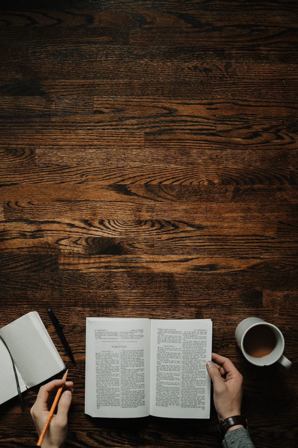 Person reading a book on a wooden table with a cup of coffee and a notebook. - Study, Bible