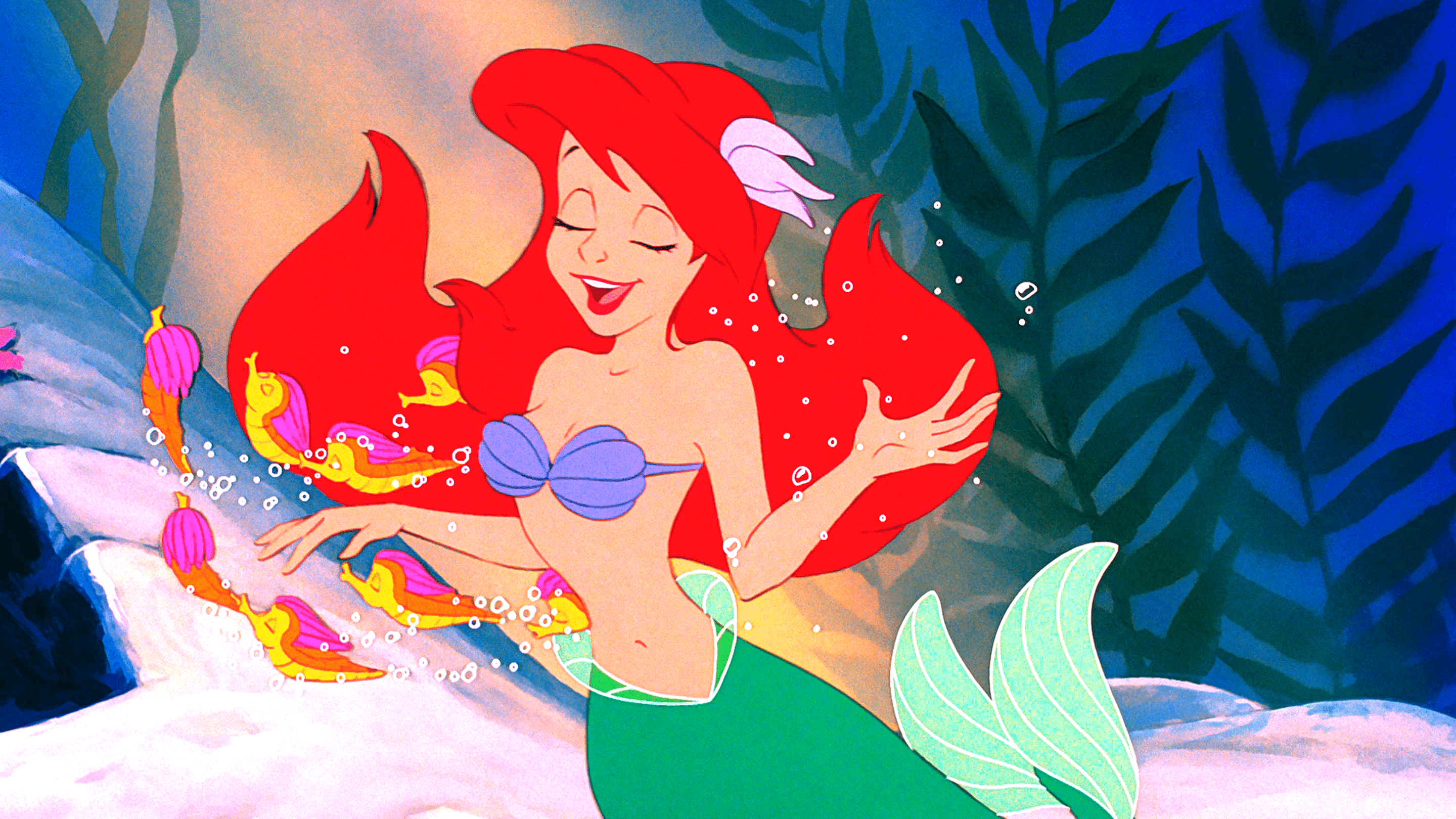 The little mermaid is holding a fish in her hand - Ariel