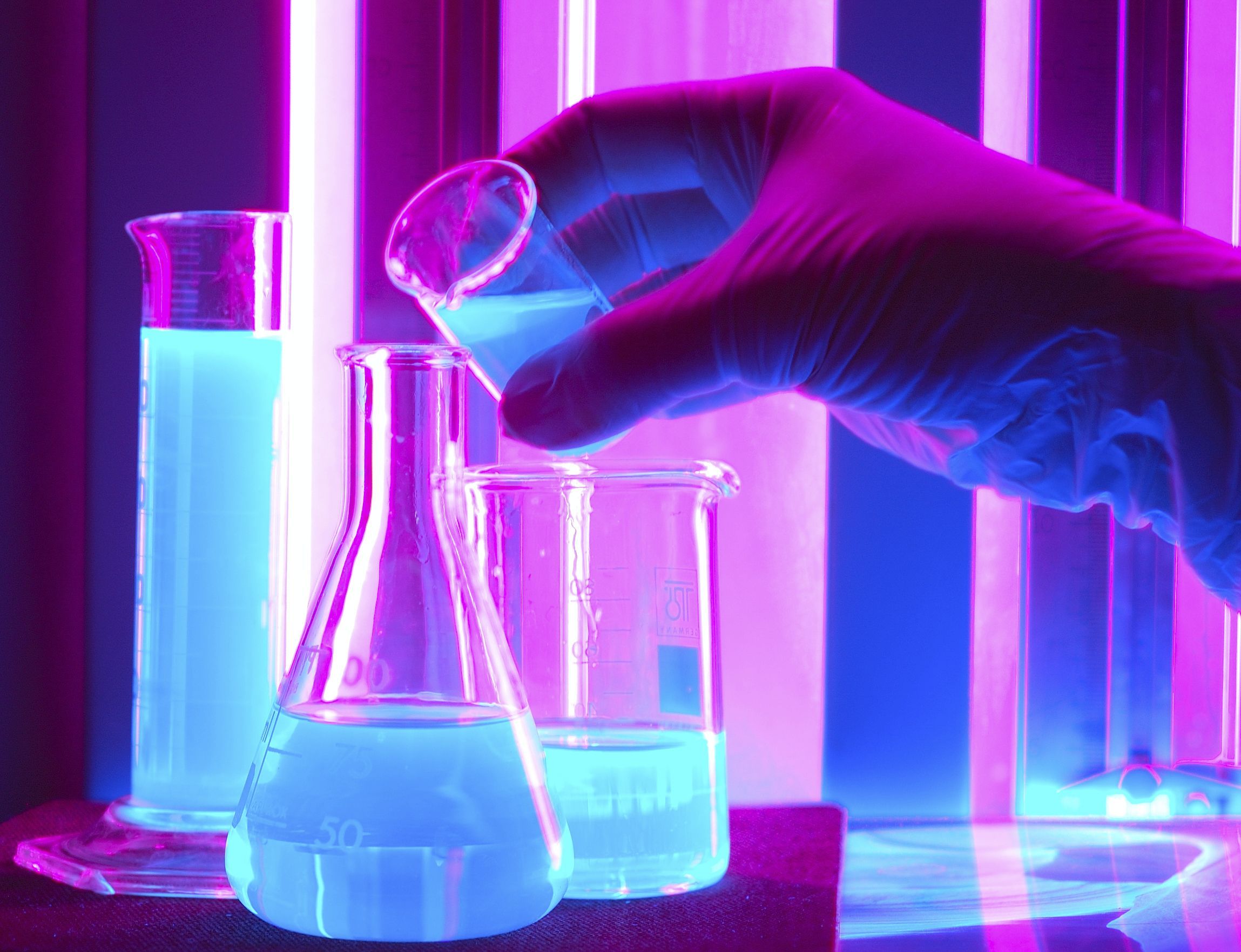 A person in gloves is holding up some liquid - Chemistry
