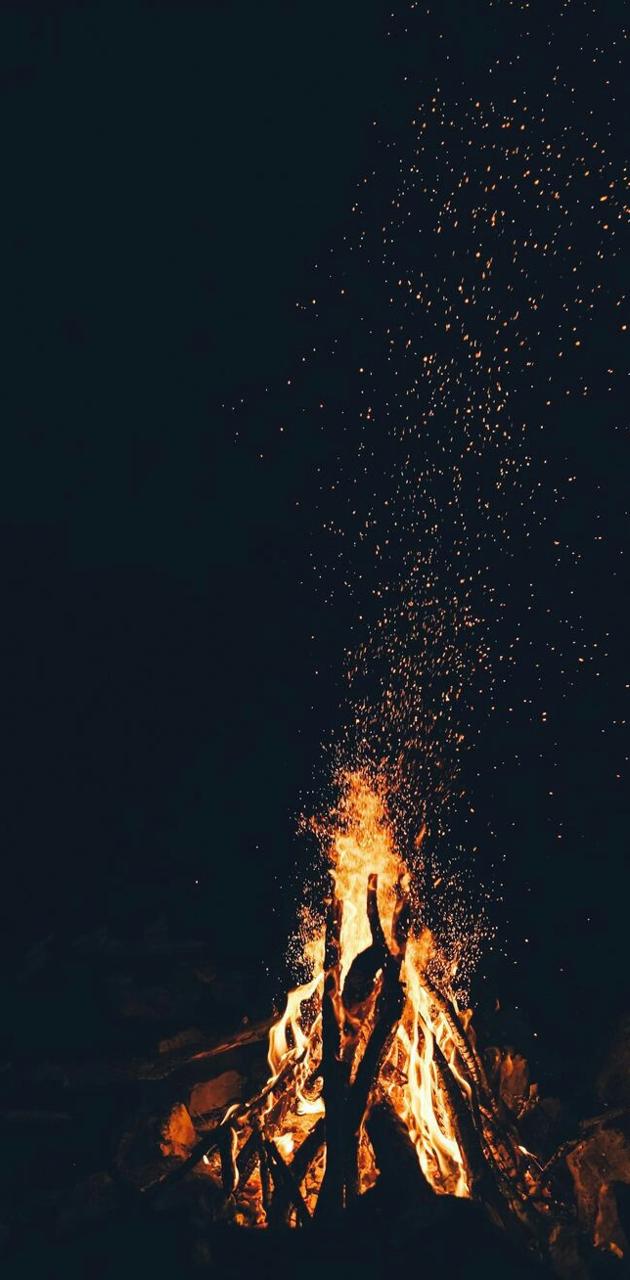 A bonfire at night with sparks flying - Camping