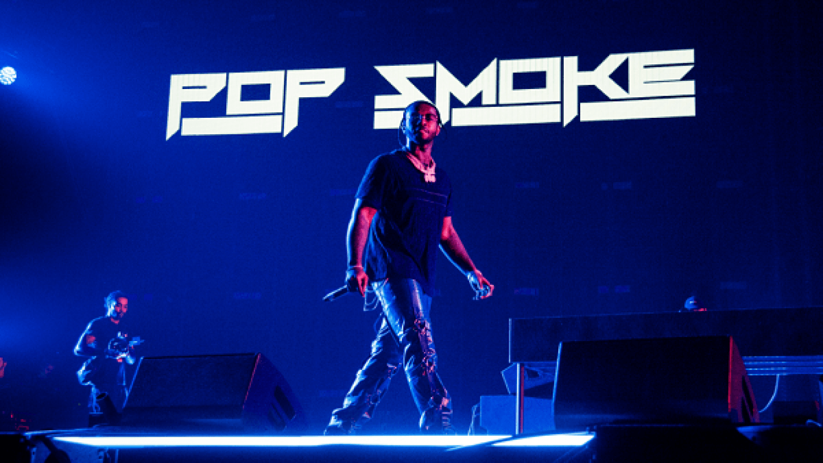 A man is standing on stage with music playing - Pop Smoke