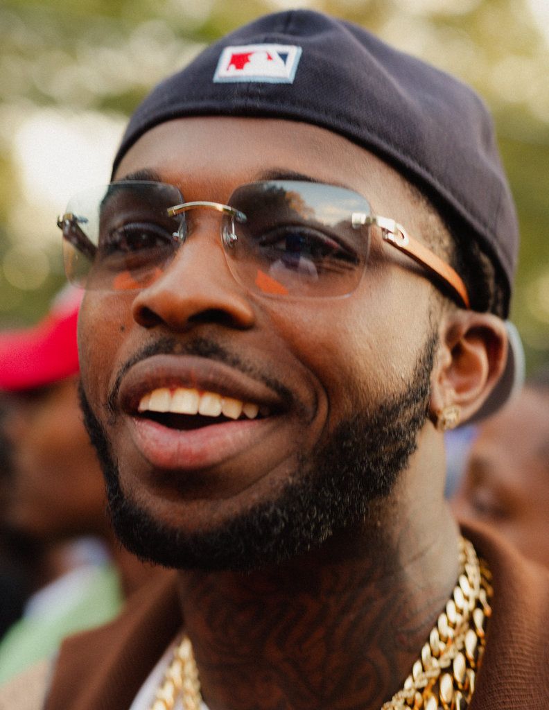 A man with sunglasses and gold chains smiling - Pop Smoke