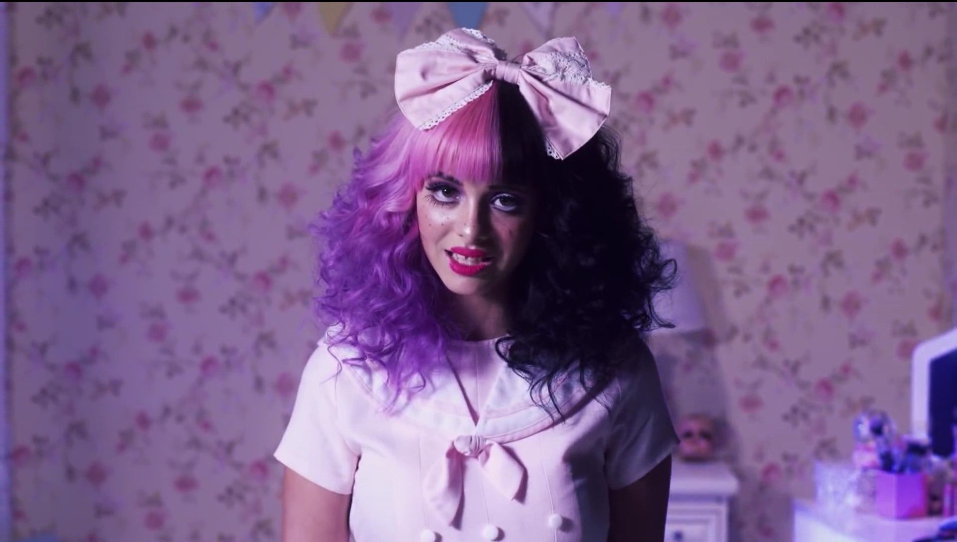 A woman with pink hair and a pink bow in her hair. - Melanie Martinez