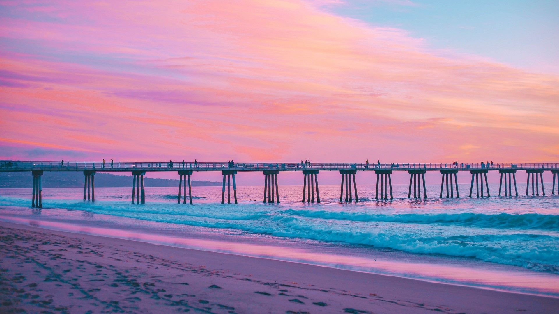 A pier stretches out into the ocean at sunset. - Beach, California