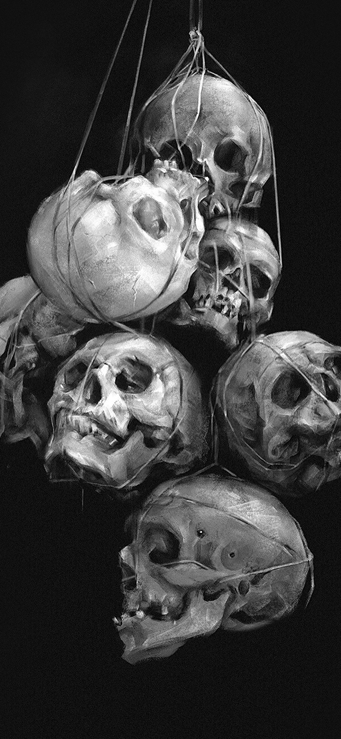 Black and white image of a collection of skulls hanging from strings. - Skull