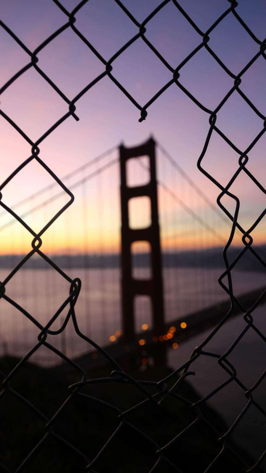 Golden Gate Bridge through a chain link fence during sunset - Sunrise