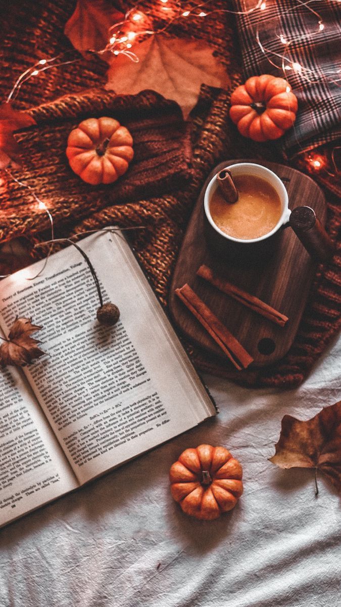 A book, a cup of coffee, a pumpkin spice latte, a blanket, and autumn leaves. - Fall
