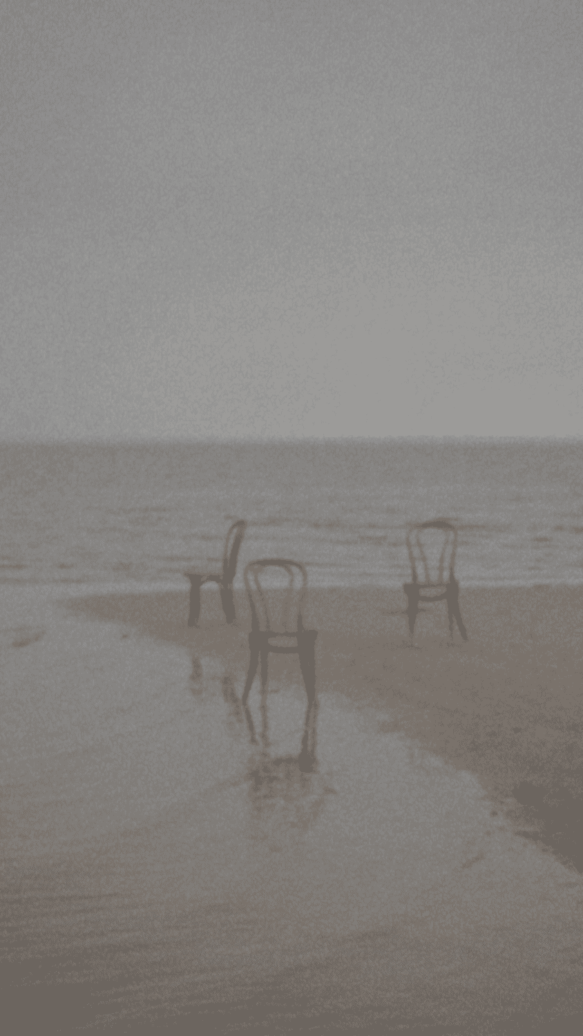 A sepia photograph of two chairs and a table on a beach. - Beach