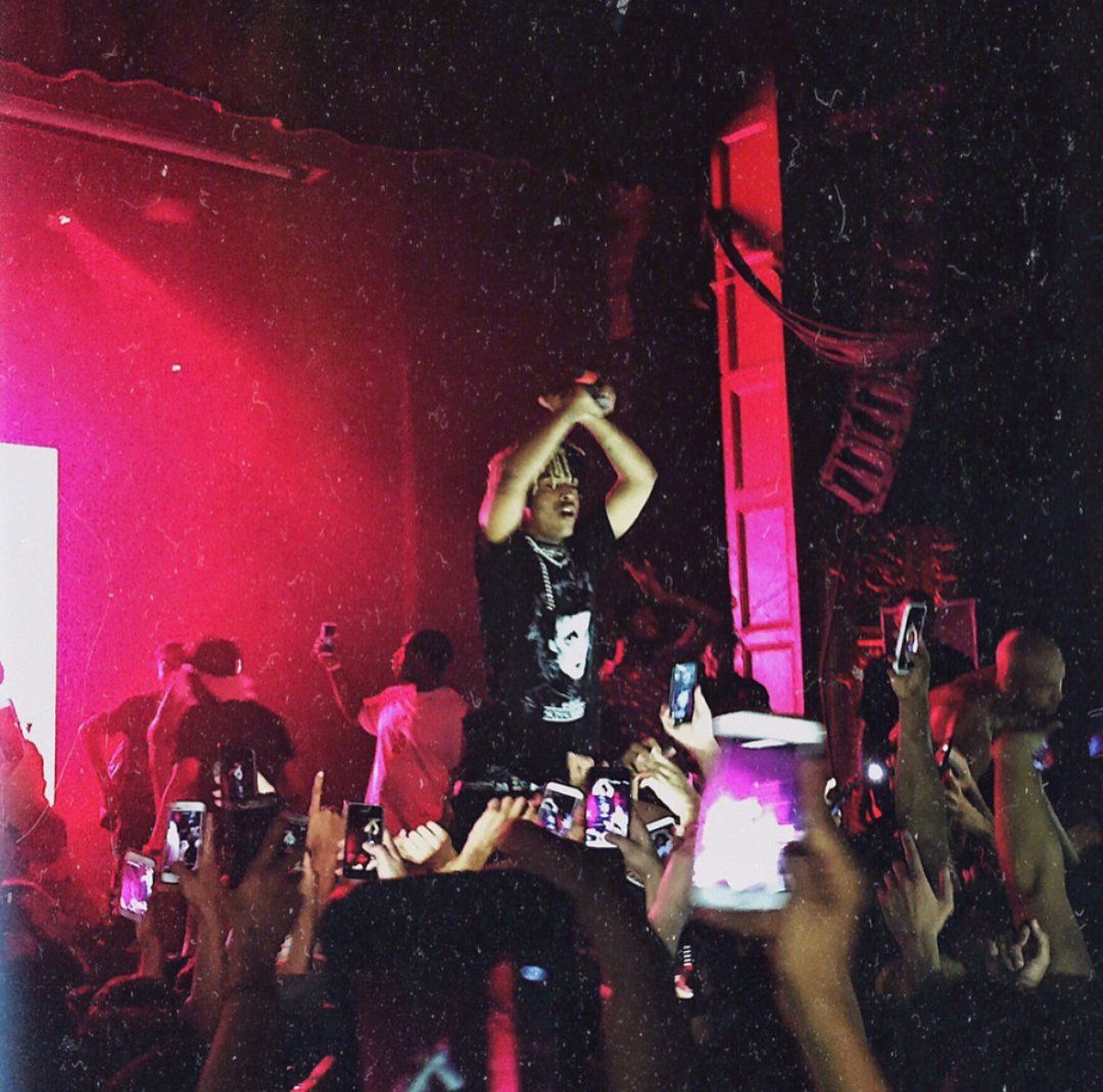 A man standing on stage with his arms raised - XXXTentacion