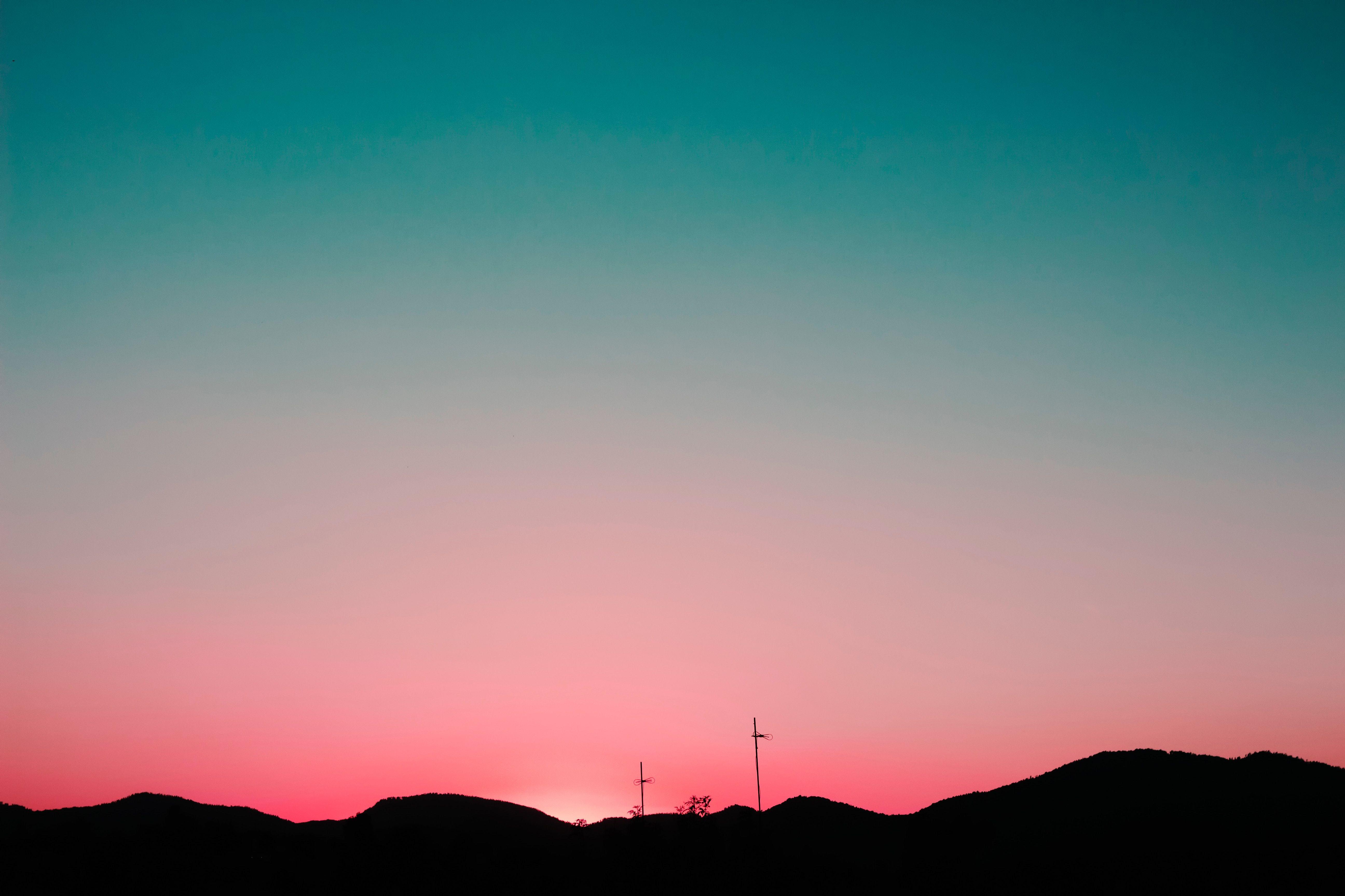 A sunset over a mountain range with wind turbines in the distance. - Sunset