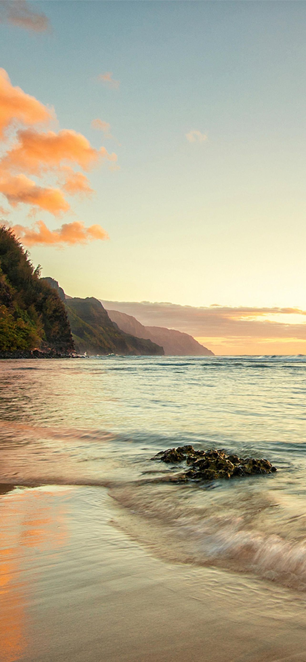 A beach with waves and sand at sunset - Hawaii