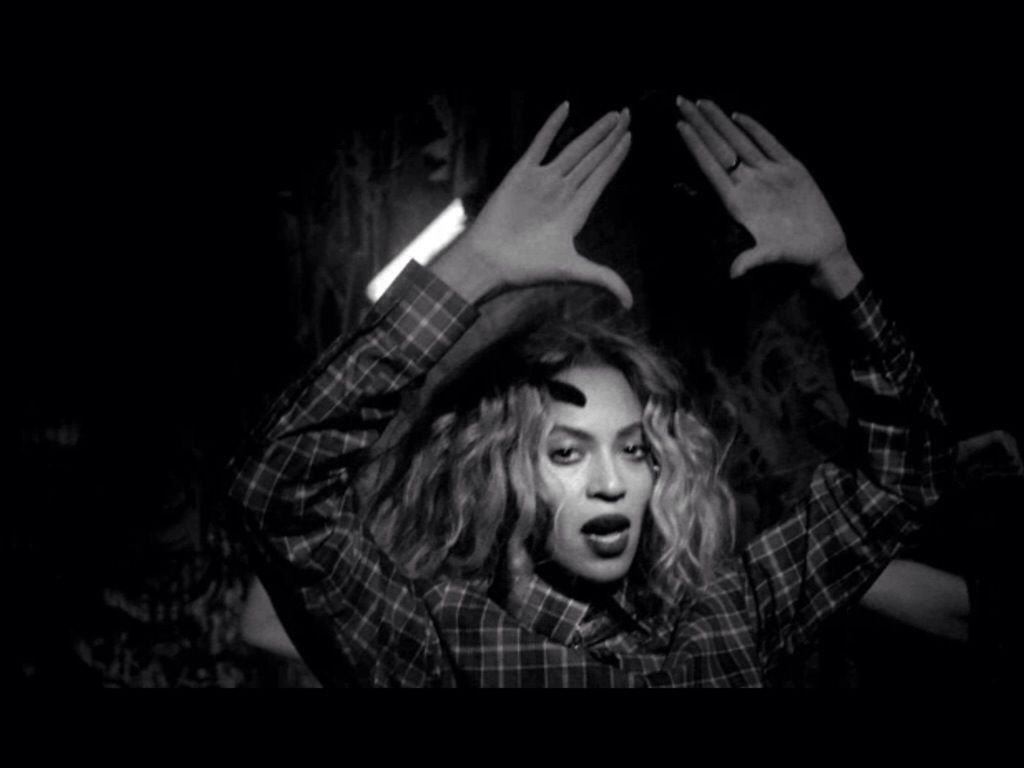 A woman in plaid shirt is holding her hands up - Beyonce